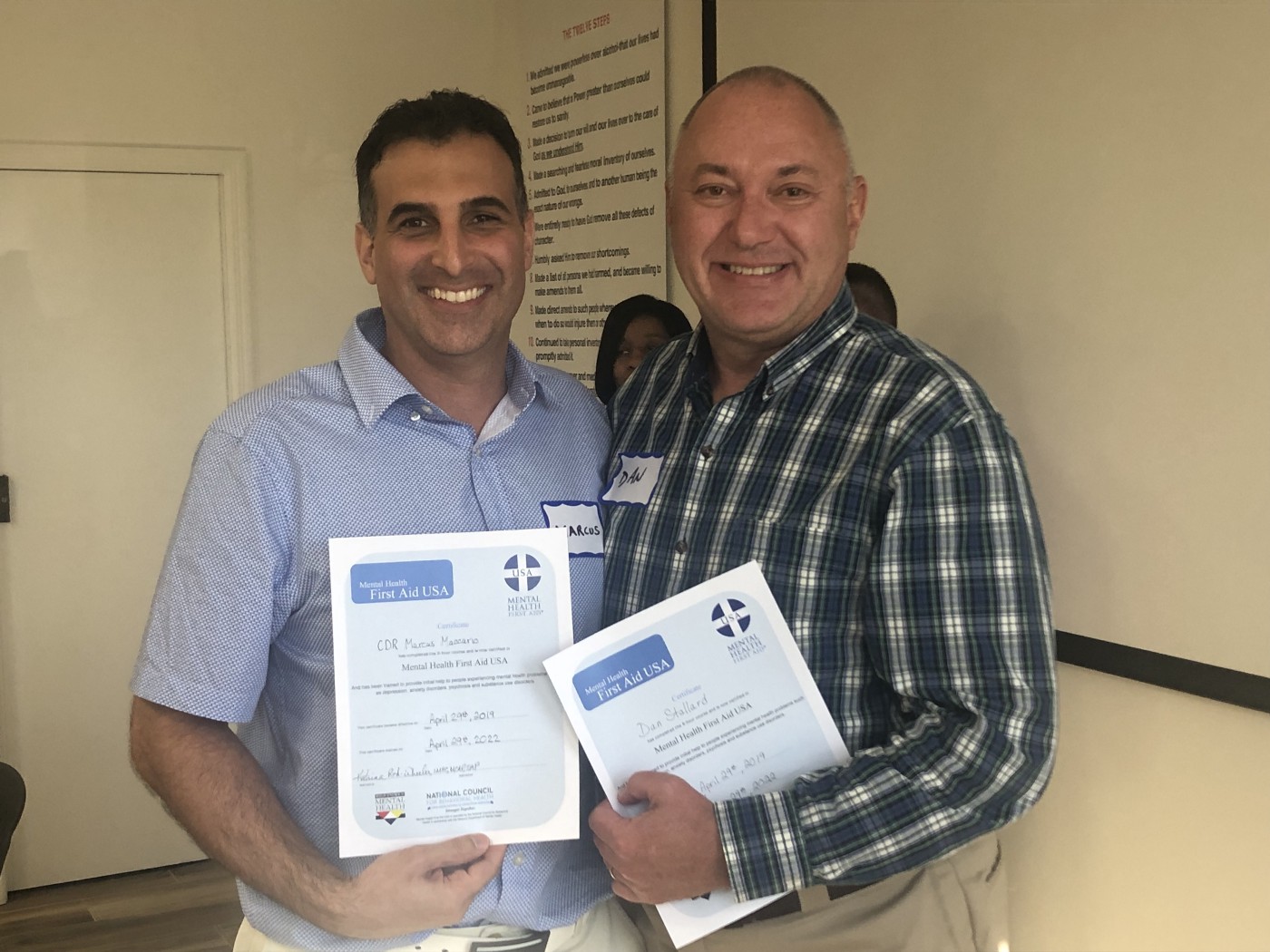 Two individuals hold certificates that read "Mental Health First Aid USA"