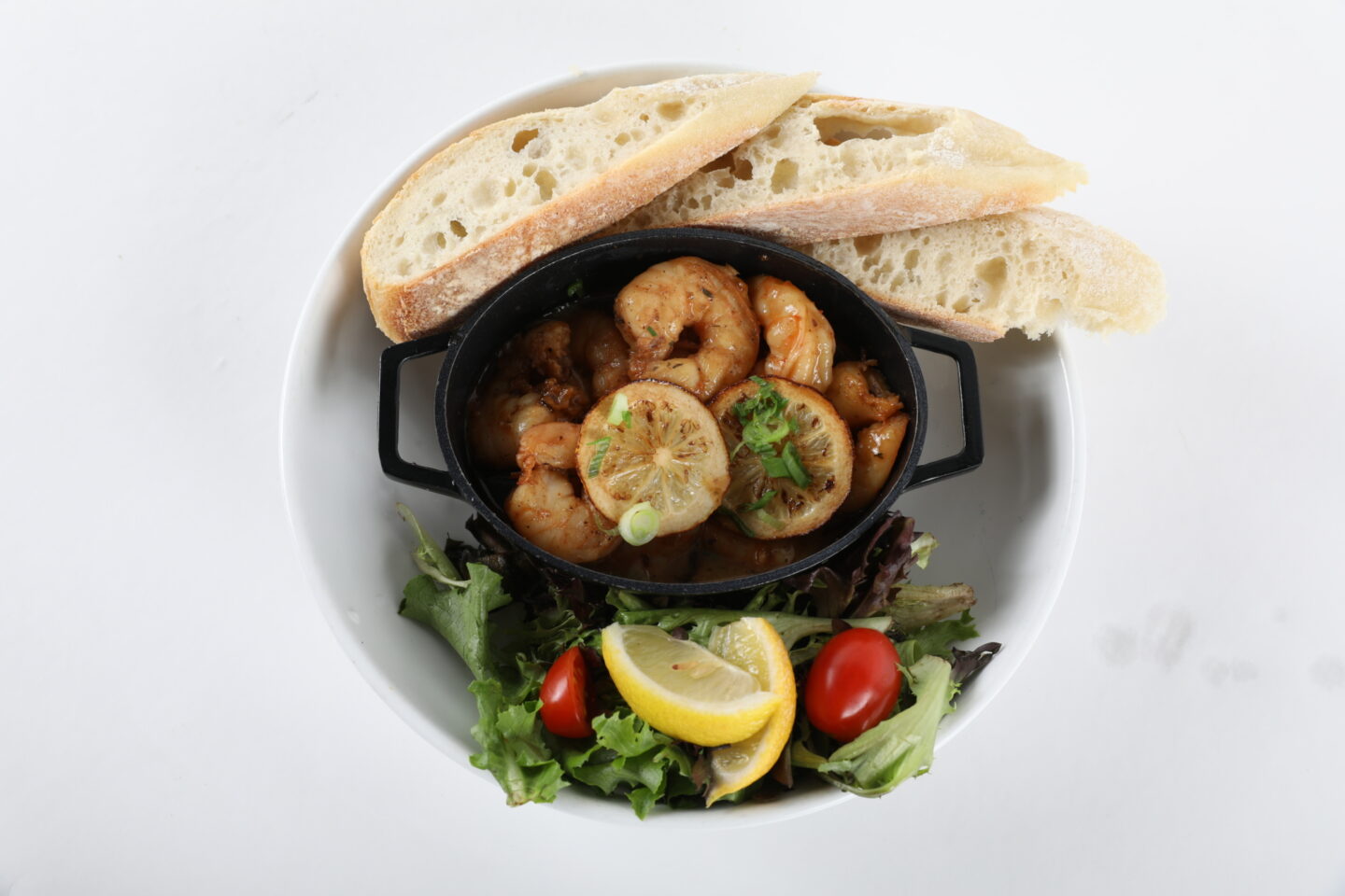 Plated meal which includes shrimp, salad, and bread