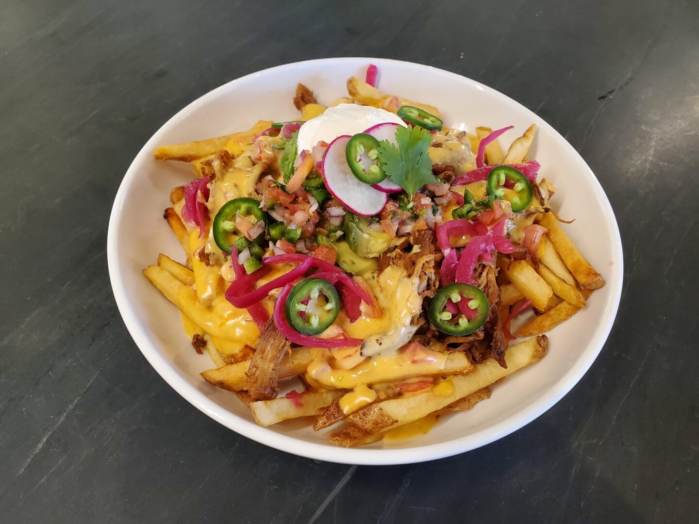 Plated meal which includes pulled pork french fries
