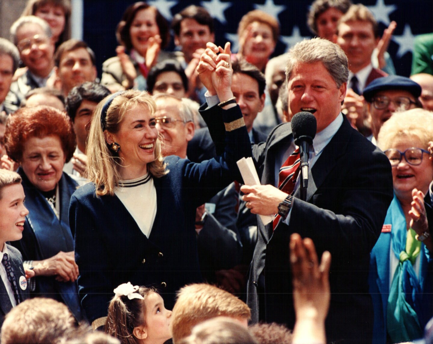 Then-Governor Bill Clinton and Hillary Clinton stand amid a crowd at a rally