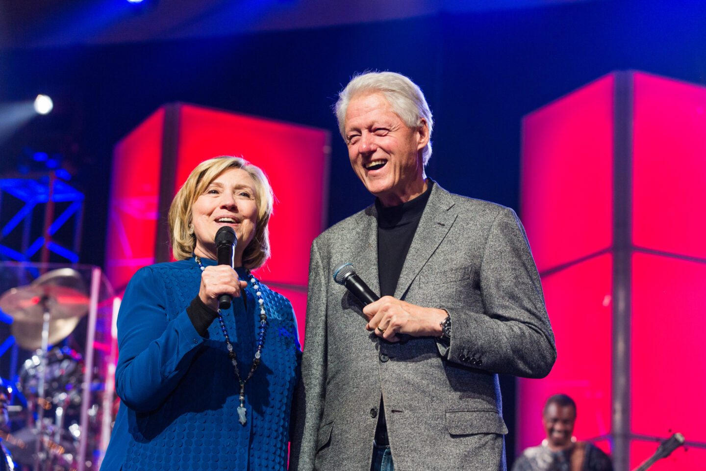 Secretary Clinton and President Clinton speak on stage during a concert.