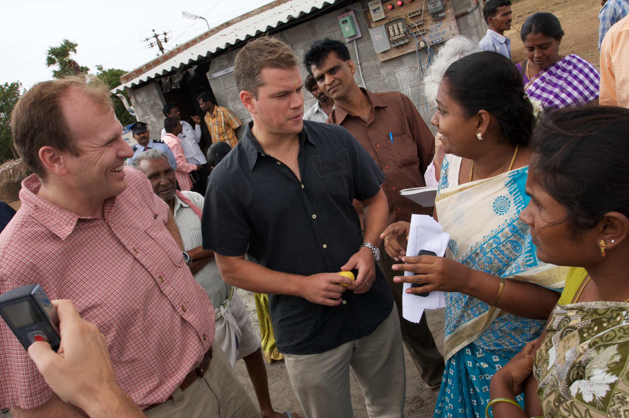 Matt Damon and Gary White speak with two individuals in India
