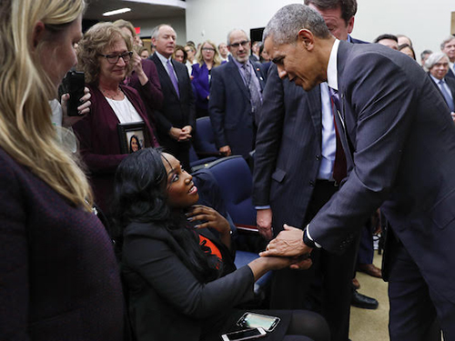 President Barack Obama shakes an individual's hand in a crowded room