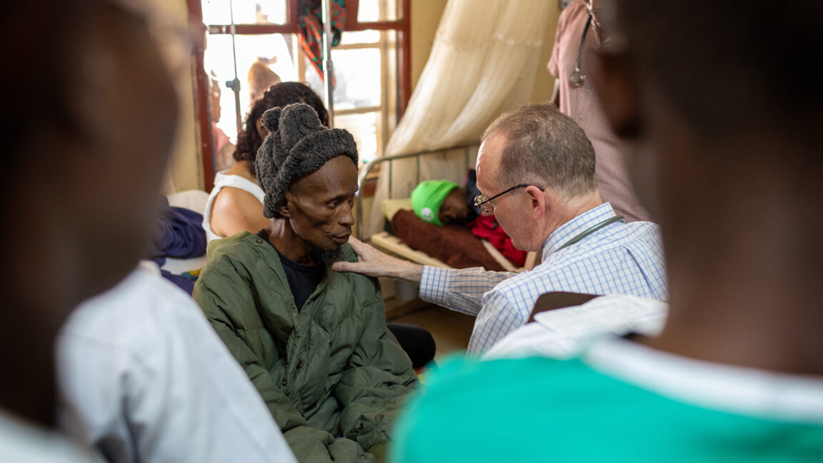 Dr. Paul Farmer places his hand on the shoulder of a patient