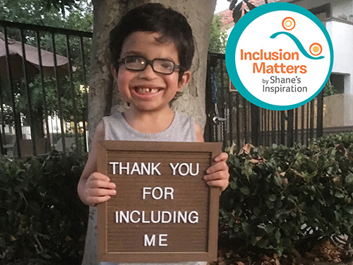A child holds a sign that reads: "thank you for including me." A graphic over the photo says: "Inclusion matters by Shane's Inspiration."