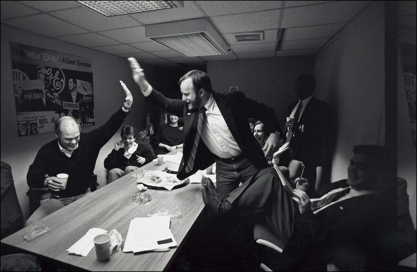 A group of individuals sit around a table and two are high-fiving