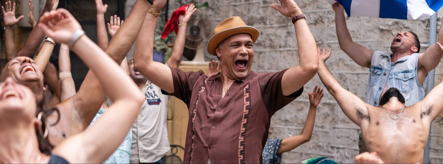 Jimmy Smits and a group of individuals raise their hands toward the sky