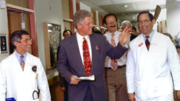 President Clinton, Anthony Fauci, and John Gallin walk through a hallway