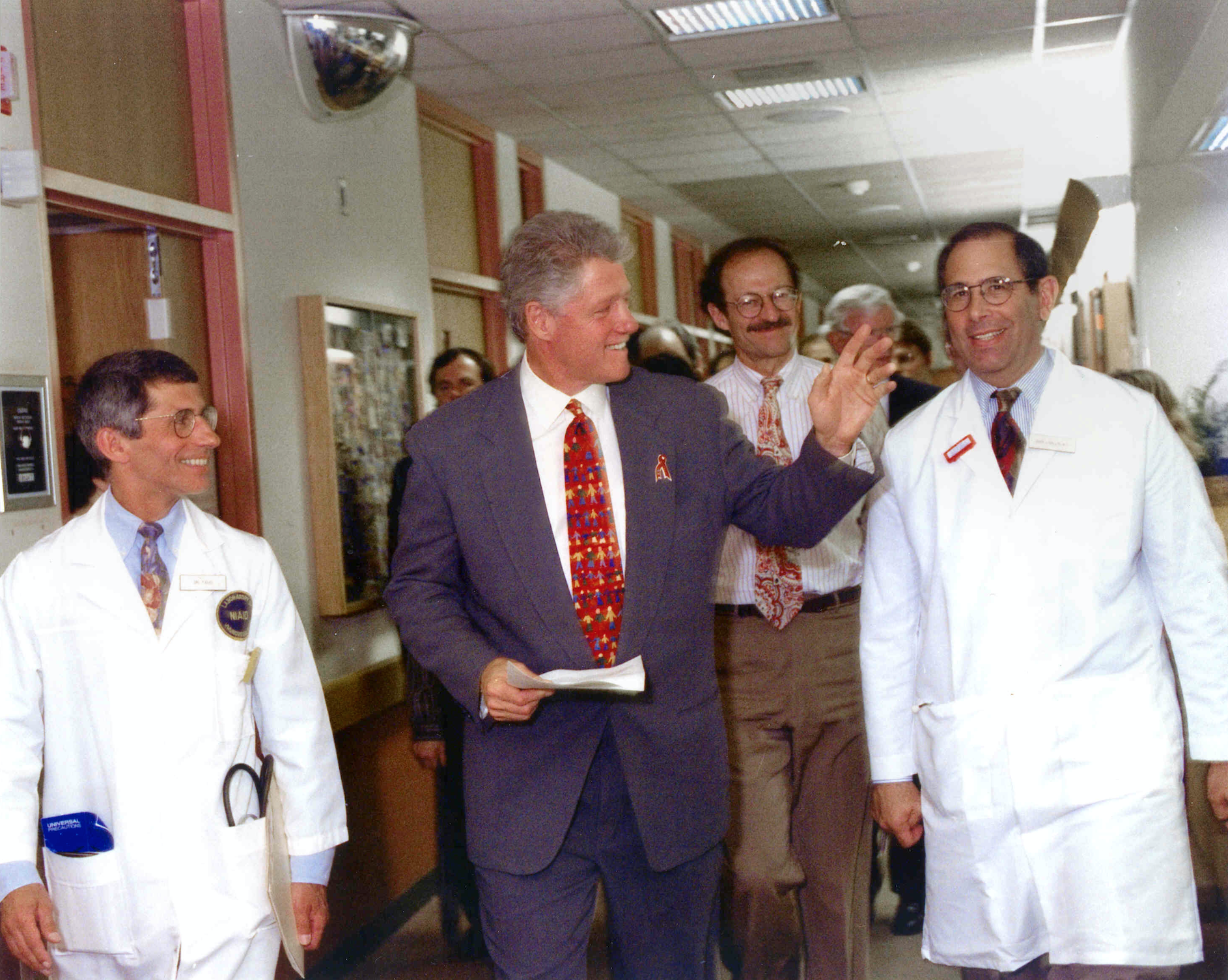 President Clinton, Anthony Fauci, and John Gallin walk through a hallway