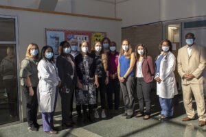 Chelsea Clinton poses for a photo with a large group of individuals. All are wearing medical masks.