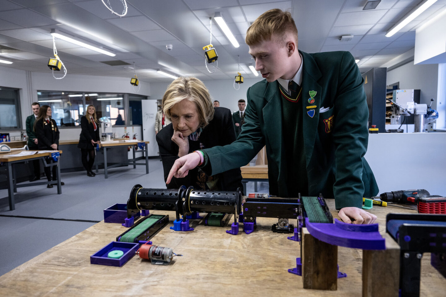 Secretary Clinton looks on as a student previews an educational project