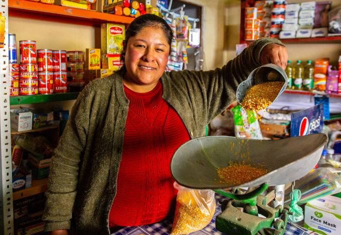 A woman, who is a beneficiary of Pro Mujer, from Bolivia stands while working in her business.