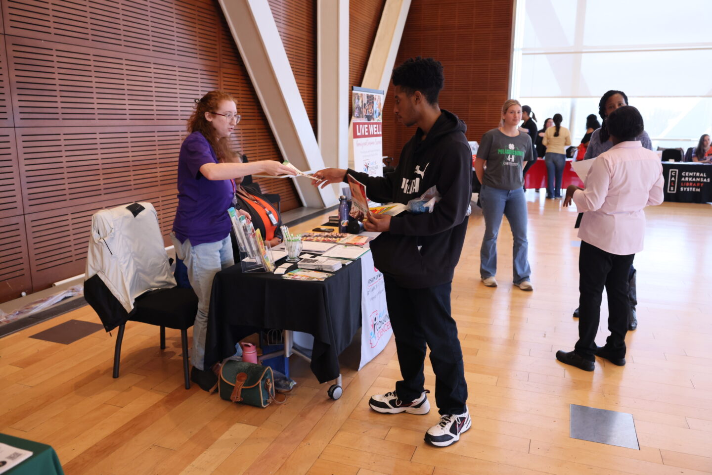 Student at a community service learning fair receiving a pamphlet from an organization